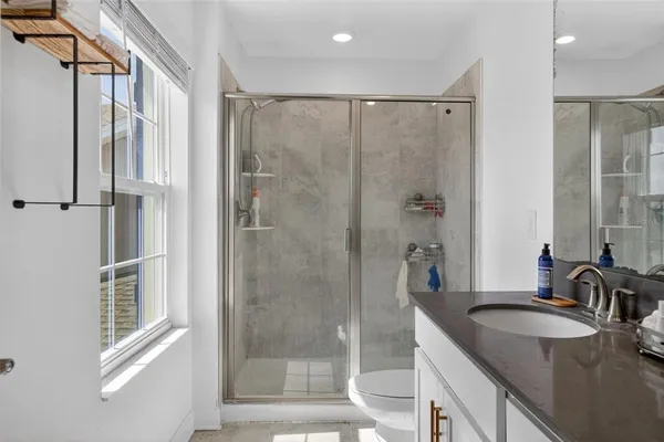 a bathroom with a granite countertop sink a mirror a bathtub and shower