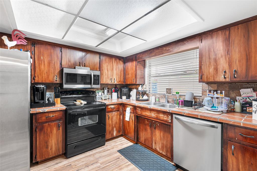 2282 Firestone Place Winter Haven, FL 33884 - Photo 6 of 34 a kitchen with stainless steel appliances granite countertop a sink a stove a refrigerator cabinets and a window