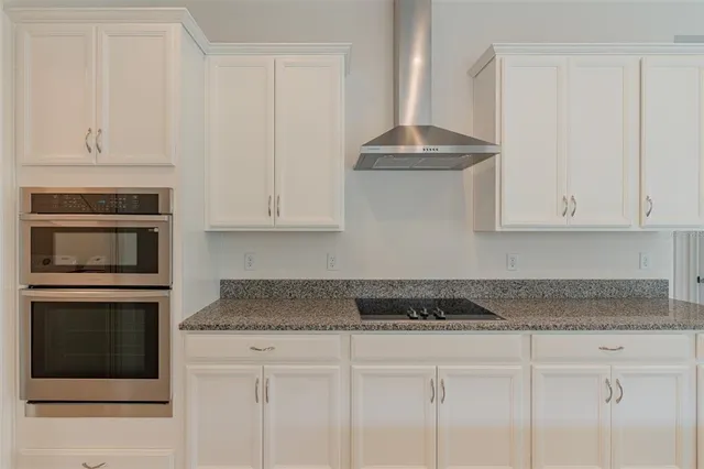 a kitchen with granite countertop a refrigerator and a stove top oven