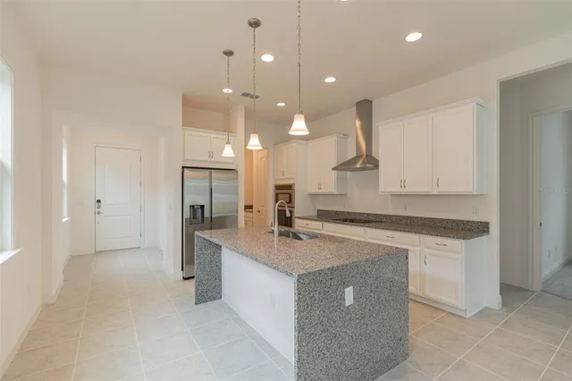 a large kitchen with kitchen island granite countertop a sink and white cabinets