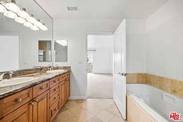 a bathroom with a granite countertop sink a bathtub a mirror and a shower