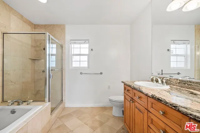 a bathroom with a granite countertop sink a toilet a mirror and shower
