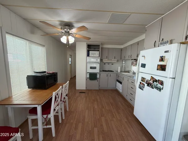 a kitchen with granite countertop a refrigerator a stove top oven a sink dishwasher and a dining table with wooden floor