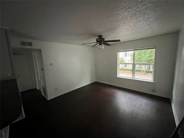 a view of an empty room with a window and wooden floor