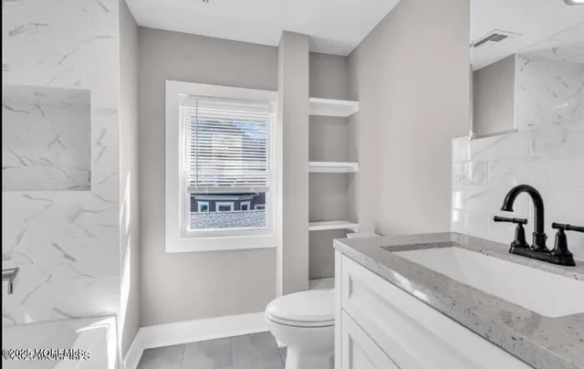 a bathroom with a granite countertop toilet a sink and a mirror