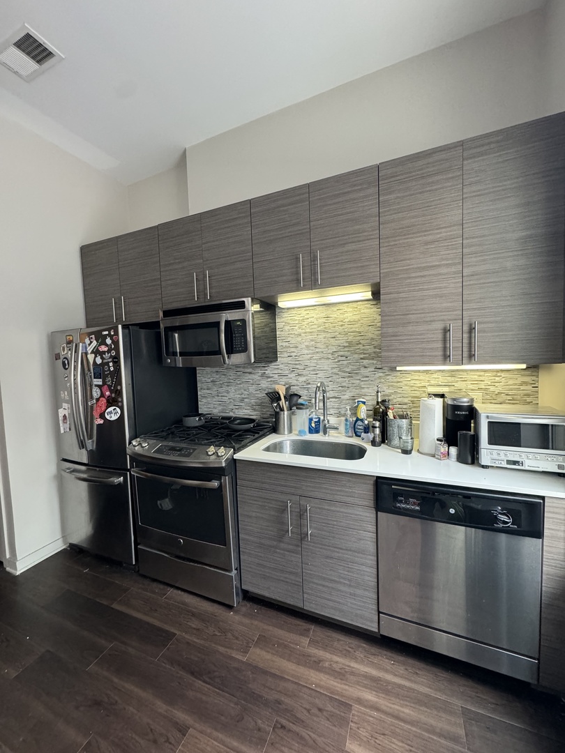 1222 West Madison Street, Unit 227 Chicago, IL 60607 - Photo 3 of 19 a kitchen with stainless steel appliances granite countertop a stove a sink dishwasher and a refrigerator