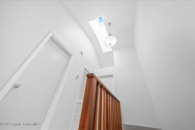 a view of staircase with railing and white walls