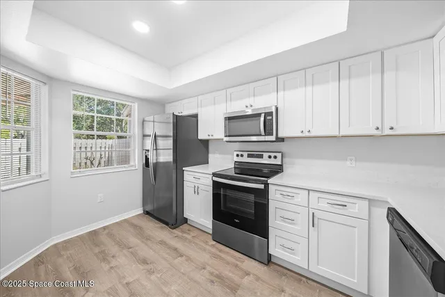 a kitchen with white cabinets stainless steel appliances and window