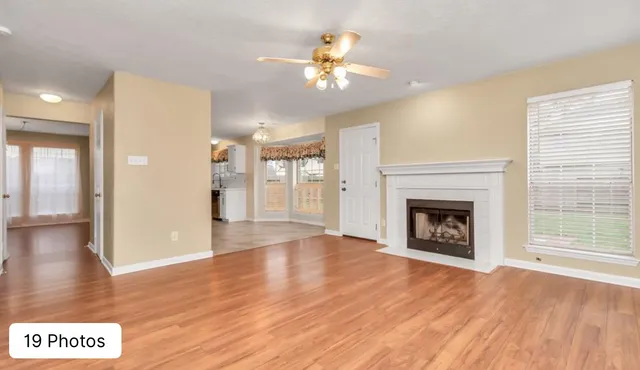 a view of an empty room with wooden floor and a fireplace