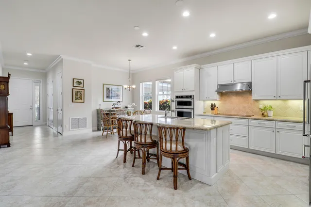 a kitchen with stainless steel appliances granite countertop a table chairs sink refrigerator and cabinets