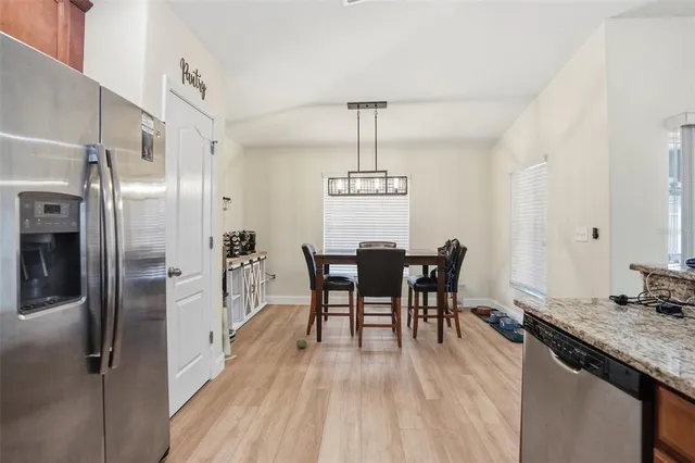 a dining room with stainless steel appliances granite countertop a kitchen island hardwood floor and a sink