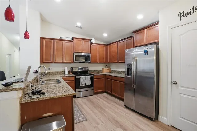 a kitchen with kitchen island granite countertop wooden cabinets a refrigerator and a stove