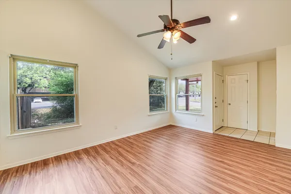 a view of an empty room with a window and wooden floor