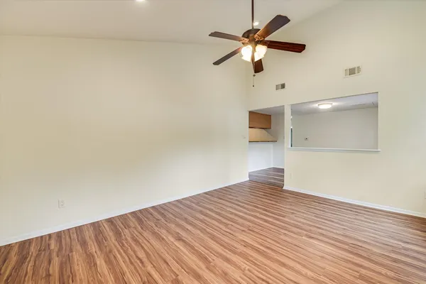a view of empty room with wooden floor and fan