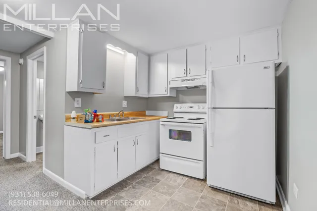 a kitchen with cabinets appliances a sink and a refrigerator