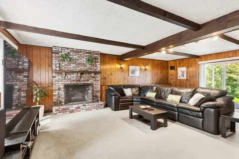a living room with furniture a fireplace and floor to ceiling windows