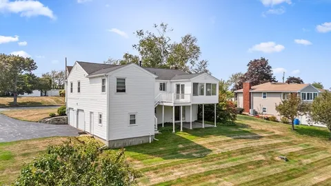 a view of a white house with a yard table and chairs under an umbrella