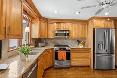 a kitchen with stainless steel appliances granite countertop a refrigerator a stove and a sink