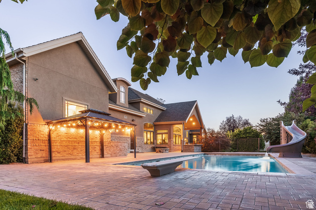 694 West Cephus Road Draper, UT 84020 - Photo 101 of 148 Expansive paver patio with a built-in swimming pool featuring a diving board and waterslide