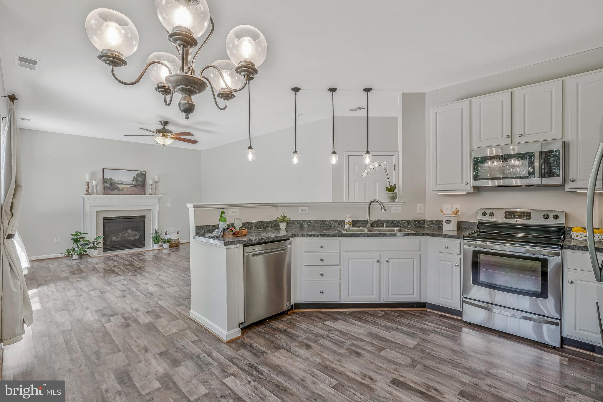 11587 Wollaston Circle Swan Point, MD 20645 - Photo 10 of 55 a kitchen with granite countertop wooden cabinets a stove a oven and a dining table with wooden floor