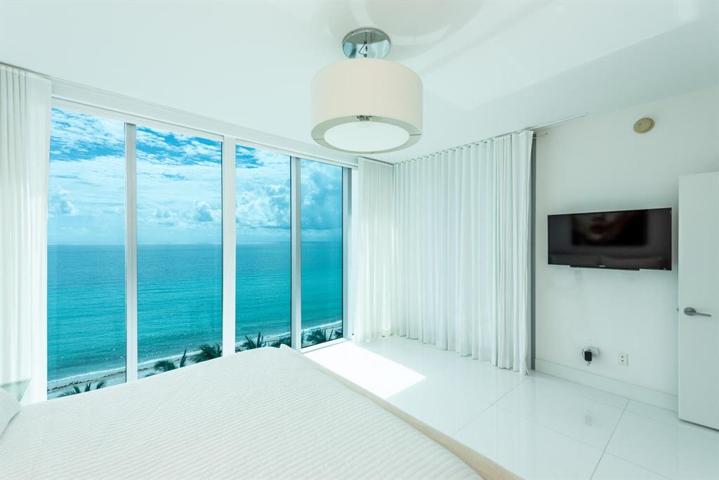 6899 Collins Avenue, Unit 908 Miami Beach, FL 33141 - Photo 12 of 19 a bedroom with a bed and a flat screen tv