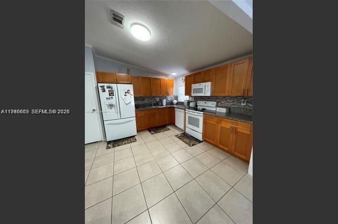 19800 Southwest 180th Avenue Miami, FL 33187 - Photo 2 of 9 a kitchen with stainless steel appliances granite countertop a stove a sink and a refrigerator
