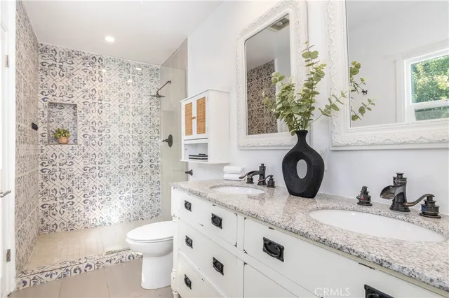a bathroom with a granite countertop sink and a toilet