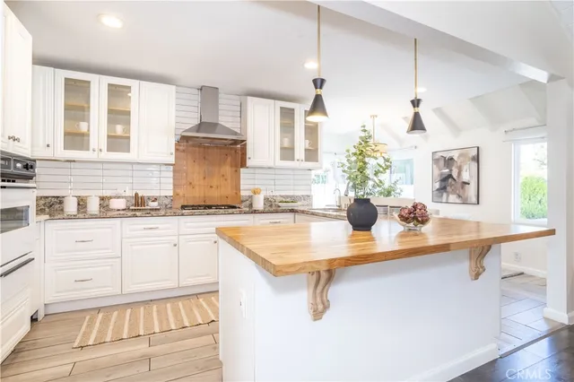 a kitchen with stainless steel appliances granite countertop a sink dishwasher and white cabinets with wooden floor