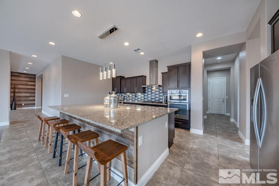 9875 Firefoot Lane Reno, NV 89521 - Photo 12 of 29 a kitchen with stainless steel appliances kitchen island granite countertop a table chairs sink and cabinets
