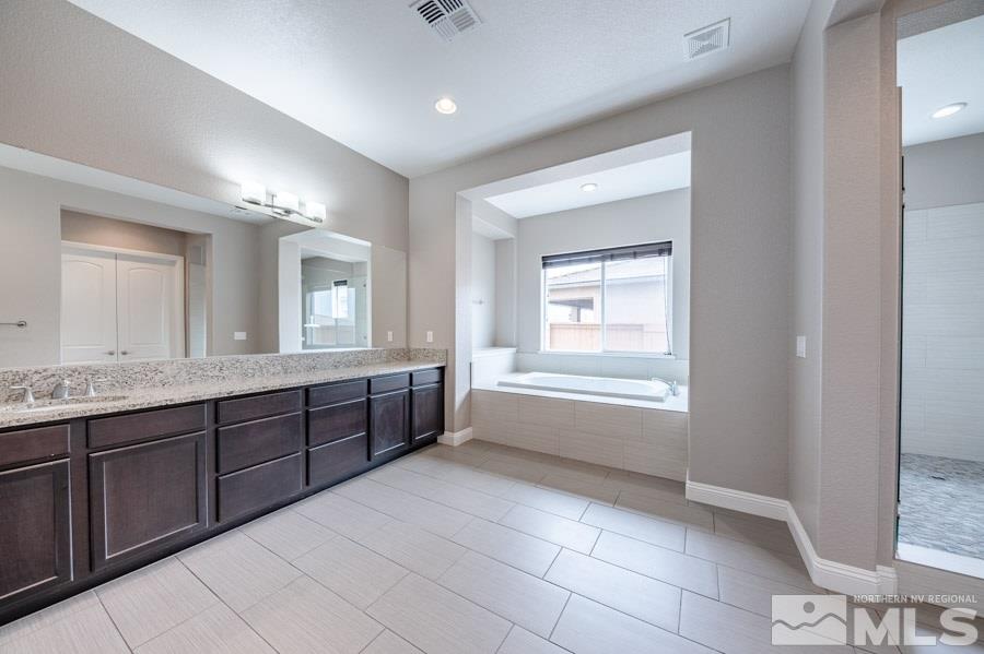9875 Firefoot Lane Reno, NV 89521 - Photo 17 of 29 a spacious bathroom with a granite countertop sink a mirror and a bathtub