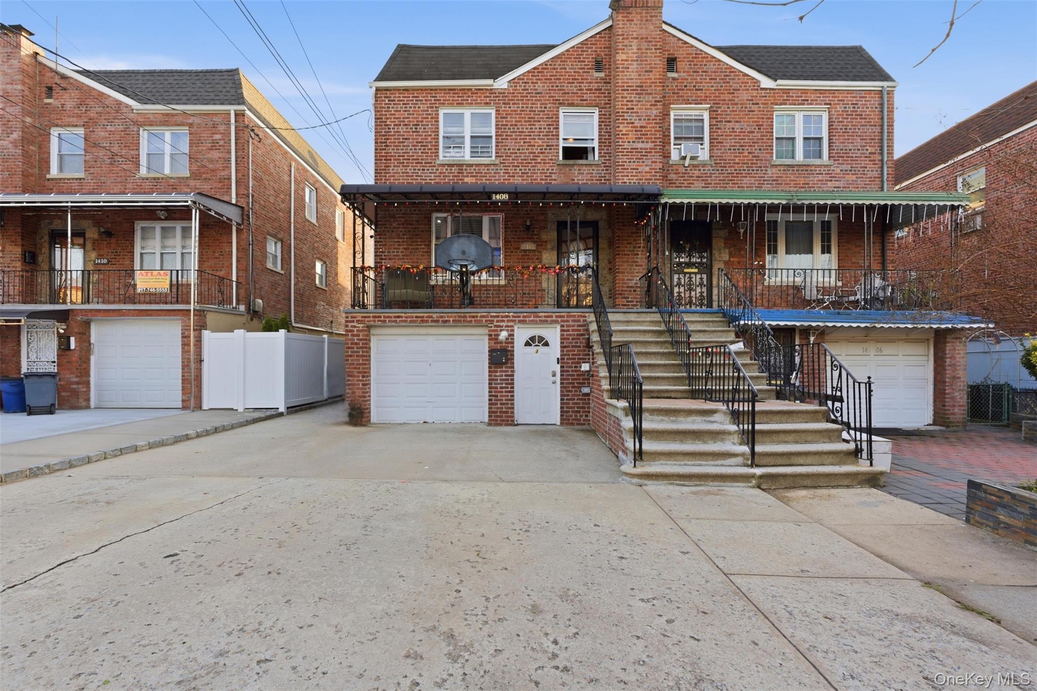 1408 Astor Avenue Bronx, NY 10469 - Photo 2 of 21 View of front of house with brick siding, driveway, a garage, a balcony, and stairway