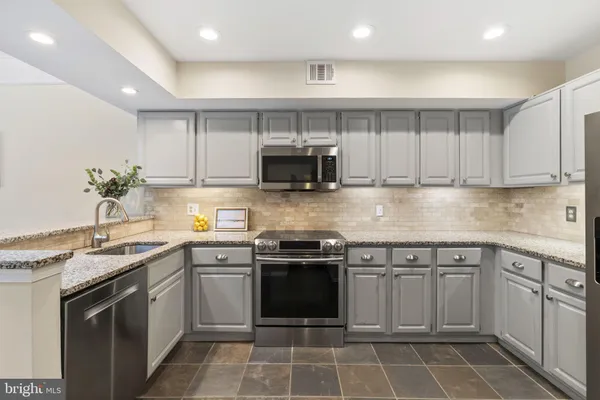 a kitchen with stainless steel appliances granite countertop a refrigerator stove a sink and microwave