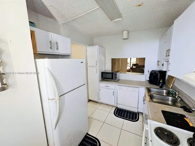 a kitchen with a refrigerator a stove top oven a sink and cabinets