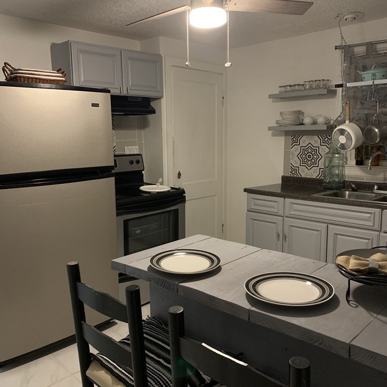 23 Notre Dame Street Springfield, MA 01104 - Photo 16 of 28 a kitchen with stainless steel appliances a table chairs and a refrigerator