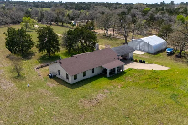 an aerial view of a house with pool and a yard