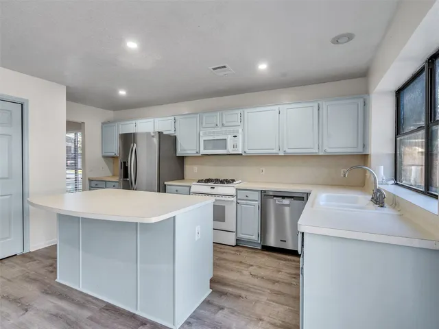 a kitchen with stainless steel appliances white cabinets sink and stove
