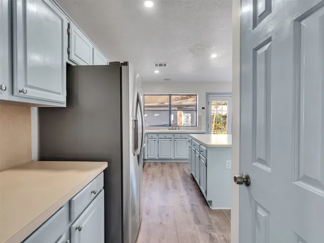 a kitchen with a refrigerator a sink and dishwasher with wooden floor
