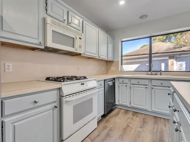 a kitchen with granite countertop white cabinets and white appliances