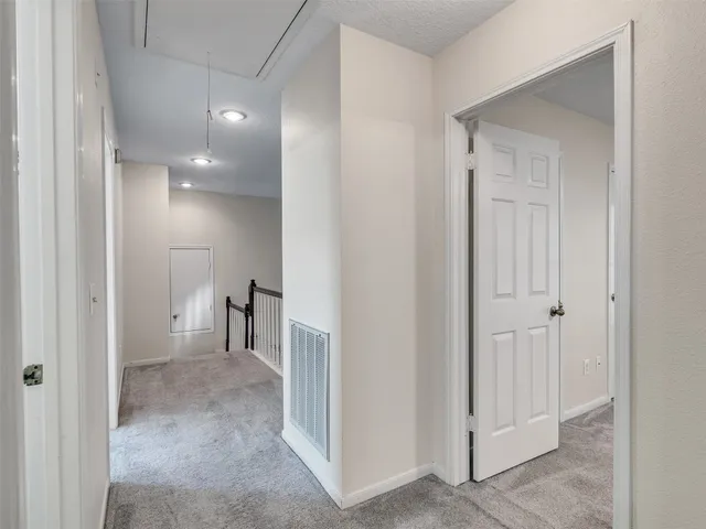 a view of a hallway with closet and a bathroom