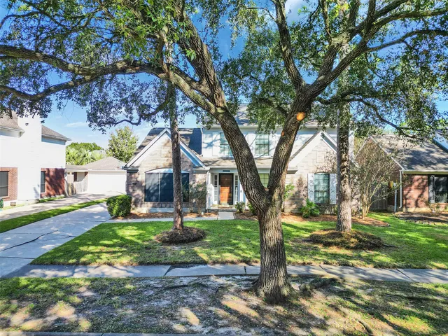 a front view of a house with a yard and large trees
