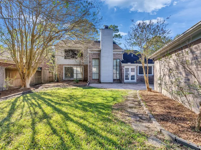 a view of a house with a small yard and large tree