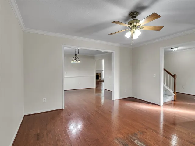 a view of an empty room with wooden floor and a ceiling fan