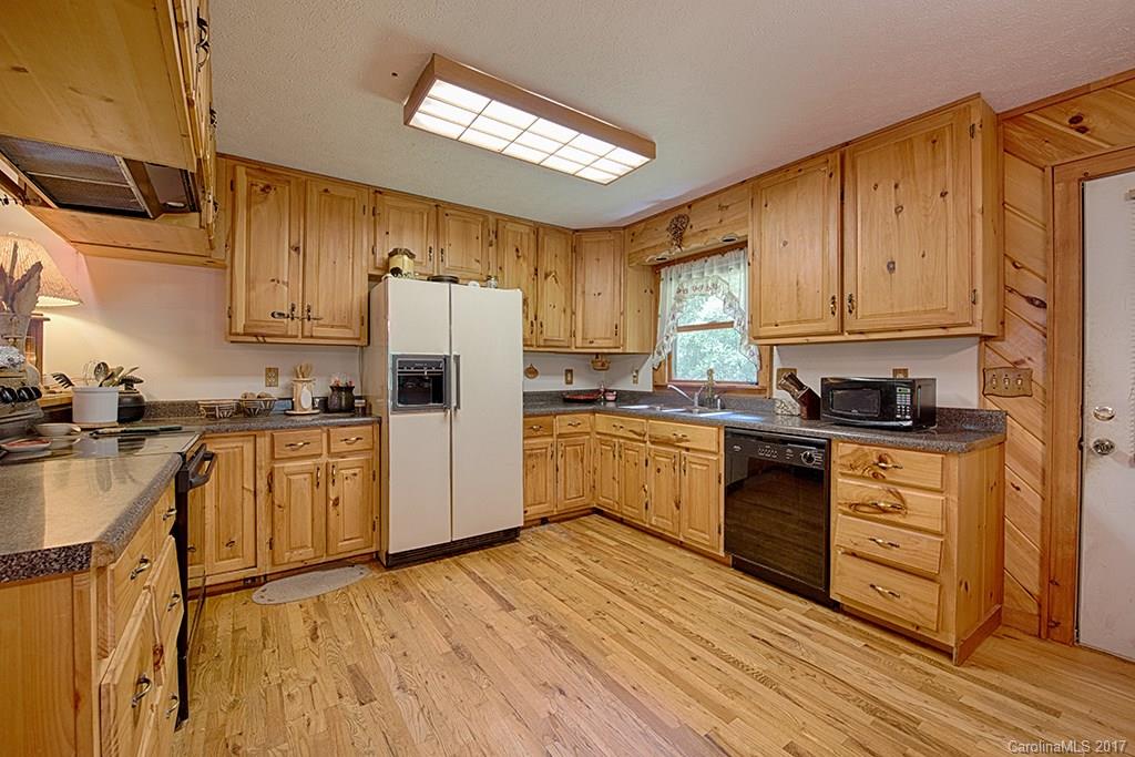 95 Straightup Road Maggie Valley, NC 28751 - Photo 3 of 24 a kitchen with granite countertop wooden floors white cabinets and stainless steel appliances