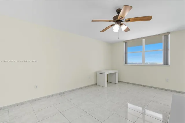 a view of an empty room with a ceiling fan and a window