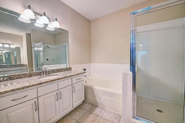 a bathroom with a granite countertop sink a mirror and a bathtub
