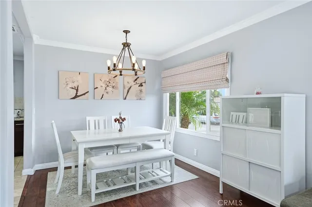 a dining room with wooden floor a chandelier a wooden table and chairs