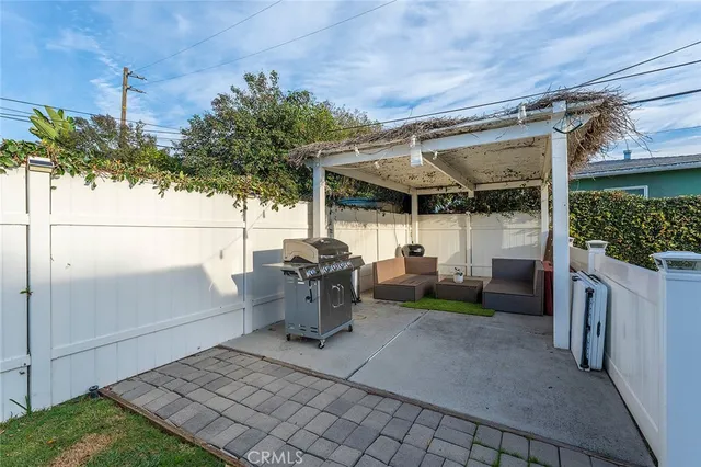 a view of a patio with table and chairs under an umbrella with a small yard