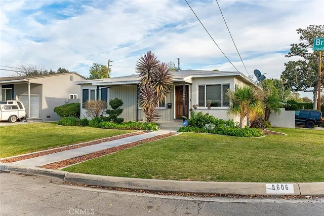 a front view of a house with a yard and potted plants