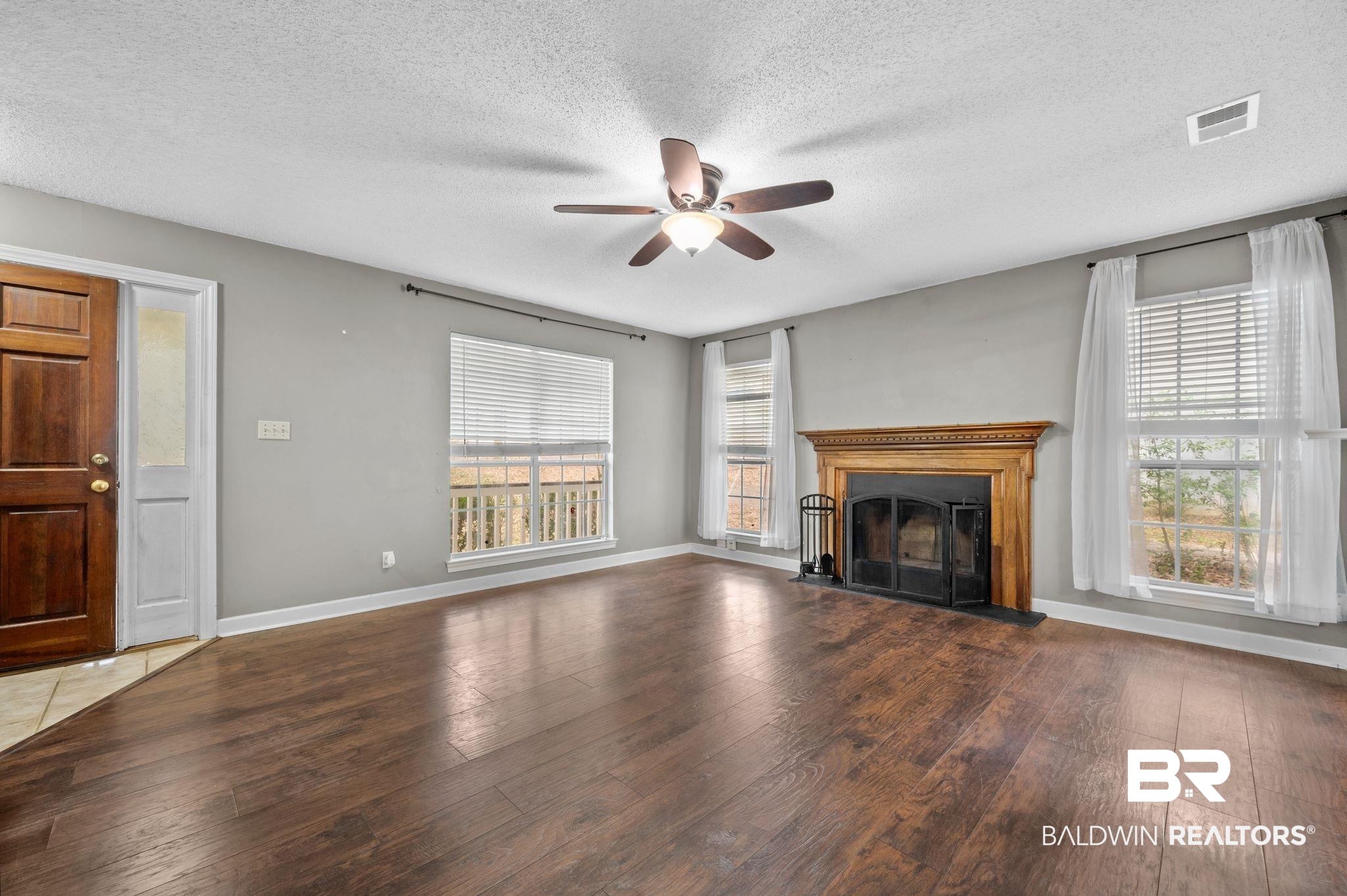 100 Montclair Loop Daphne, AL 36526 - Photo 27 of 39 Unfurnished living room with a textured ceiling, dark hardwood / wood-style floors, a healthy amount of sunlight, and ceiling fan