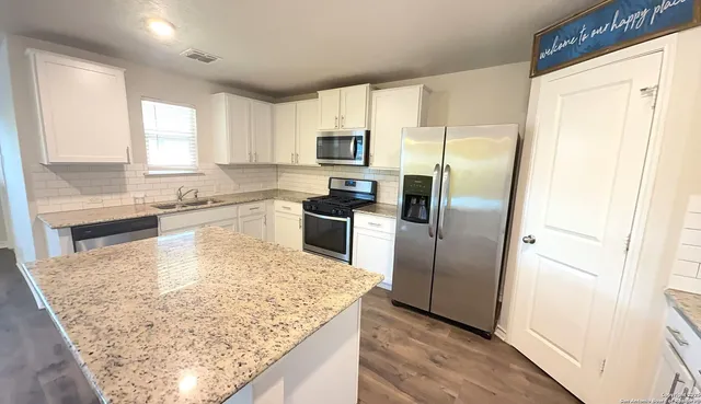 a kitchen with granite countertop a refrigerator and a sink